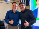 Jezreel Lescano e André Salineiro posam lado a lado durante evento, sorrindo e fazendo sinal de positivo.